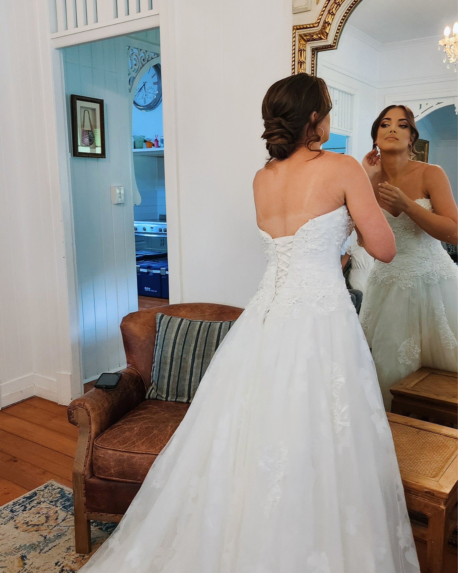 Bridal makeup and hair during wedding morning preparation, bride adjusting look in mirror, soft glam style